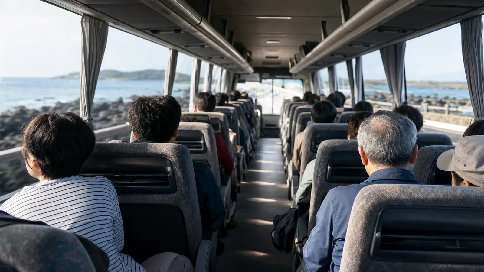 제주 해안도로를 지나는 전세버스 안에서 창밖을 보는 단체 승객